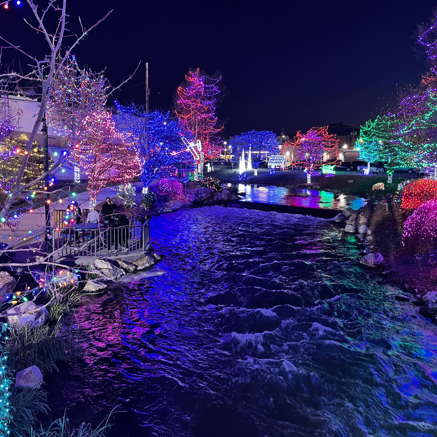 Professional holiday lighting installation on luxury residential home at dusk with snow-covered landscape in Treasure Valley